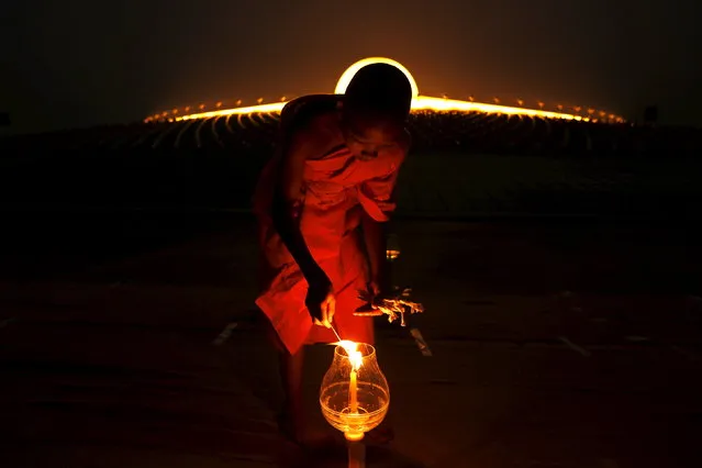 A Buddhist monk lights a candle at Wat Phra Dhammakaya during a ceremony on Makha Bucha Day in Pathum Thani province, north of Bangkok February 22, 2016. The Dhammakaya temple is regarded as the country's richest Buddhist temple. Makha Bucha Day honours Buddha and his teachings, and falls on the full moon day of the third lunar month. (Photo by Jorge Silva/Reuters)