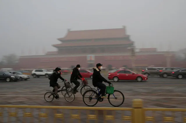 People wearing masks cycle past Tiananmen Gate during the smog after a red alert was issued for heavy air pollution in Beijing, China, December 20, 2016. (Photo by Jason Lee/Reuters)
