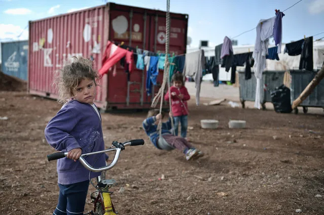 A child looks on at the Ritsona refugee camp, north of Athens, on December 21, 2016. There are over 60,000 refugees and migrants trapped in Greece after EU and Balkan countries further north shut their borders in March. (Photo by Louisa Gouliamaki/AFP Photo)