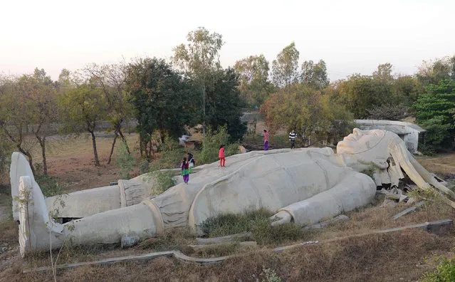 Indian children run over an incomplete model of a large male figure based on the character Lemuel Gulliver from the classic novel Gulliver's Travels, which was being used to teach youths about bodily functions, and had been receiving foreign funds for its completion, at the Navsarjan Trust's centre in Nani Devti village near Ahmedabad on December 23, 2016. An Indian charity running schools for Dalit children will close down after the government banned it from receiving foreign funds over alleged threats to national unity, officials said December 23. “We had no option left as foreign funding was the major source of running our operations”, Martin Macwan, managing trustee of the charity founded in 1988, told AFP. Charities, especially foreign-backed aid organisations like Greenpeace India, have come under increased scrutiny since a Hindu nationalist government led by Prime Minister Narendra Modi came to power in 2014. (Photo by Sam Panthaky/AFP Photo)