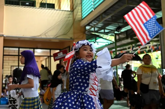A child waves flag as she wears a costume to represent USA during a school activity celebrating United Nations Day ahead of its anniversary on October 24, at an elementary school in Paranaque on October 23, 2023. (Photo by Jam Sta Rosa/AFP Photo)