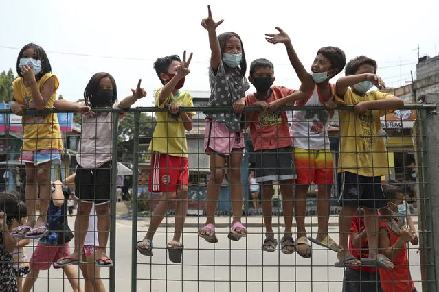 Children flash the “L” sign meaning “Fight!” during a motorcade before the burial of former Philippine President Benigno Aquino III in Quezon City, Philippines on Saturday, June 26, 2021. (Photo by Basilio Sepe/AP Photo)