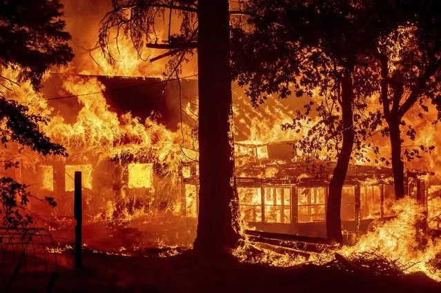 Flames from the Dixie Fire consume a home in the Indian Falls community of Plumas County, Calif., Saturday, July 24, 2021. The fire destroyed multiple residences as it tore through the area. (Photo by Noah Berger/AP Photo)