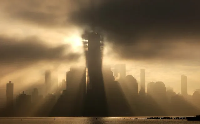 One World Trade Center casts a shadow on passing fog as the sun rises behind the skyline of lower Manhattan in New York City on December 25, 2023, as seen from Jersey City, New Jersey. (Photo by Gary Hershorn/Getty Images)