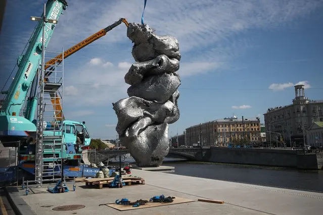 Installing the Big Clay #4 sculpture by Swiss visual artist Urs Fischer in front of a former power plant in Bolotnaya Square in Moscow, Russia on August 15, 2021. The 12-meter high aluminum sculpture is a copy of a piece of clay that the artist pugged. (Photo by Anton Novoderezhkin/TASS)
