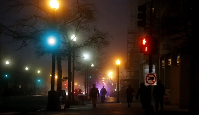 Pedestrians walk in a morning fog on 17th Street and Pennsylvania Avenue NW across from the Eisenhower Executive Office Building in Washington, Wednesday, January 15, 2014. A dense fog has caused limited visibility in the Washington area. (Photo by Charles Dharapak/AP Photo)