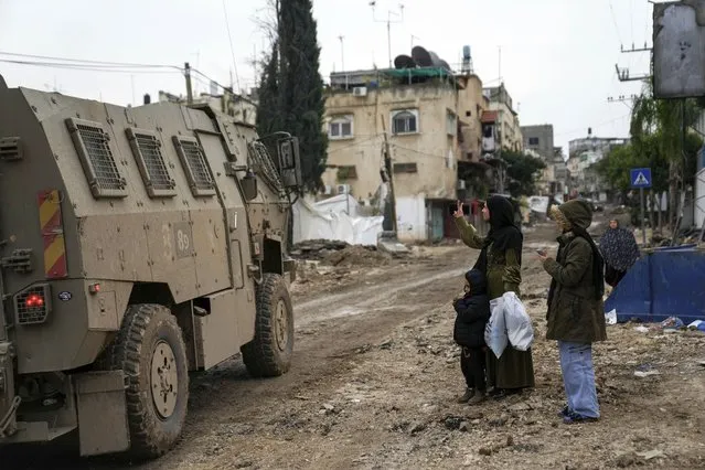 A Palestinian woman flashes a V-sign towards Israeli troops during an army raid in the Tulkarem refugee camp, West Bank, Wednesday, January 17, 2024. An Israeli airstrike killed four Palestinians during a raid in the West Bank. The military says it targeted a group of militants who had opened fire and were throwing explosives at Israeli soldiers in the Tulkarem refugee camp. The Palestinian Health Ministry says four people were killed. (Photo by Nasser Nasser/AP Photo)