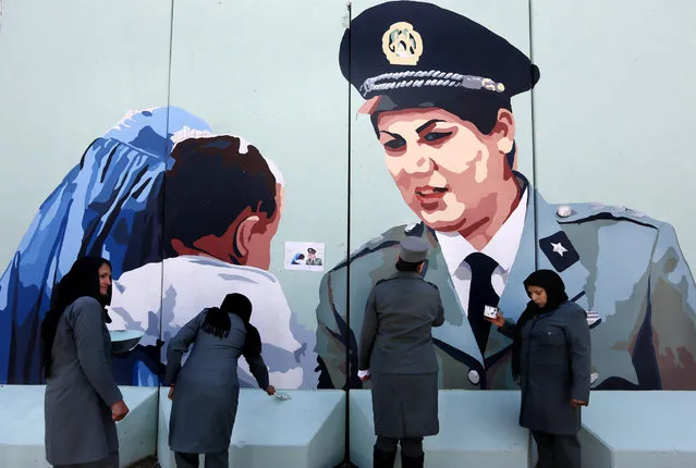 Friba Hameed, 30, an Afghan police officer, second right, helps paint part of a mural of herself on a wall outside the main gate of a police precinct to mark International Women's Day in Kabul, Afghanistan, Tuesday, March 8, 2016. (Photo by v/AP Photo)
