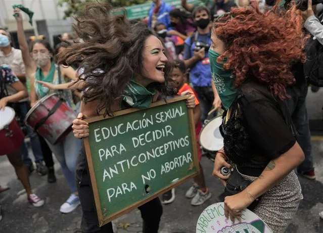 A woman holds a sign that reads in Spanish “Sеx education to decide, contraceptives to avoid abortion”, as she jumps with another woman as part of the Global Day of Action for access to legal, safe and free abortion, outside the parliament in Caracas, Venezuela, Tuesday, September 28, 2021. (Photo by Ariana Cubillos/AP Photo)