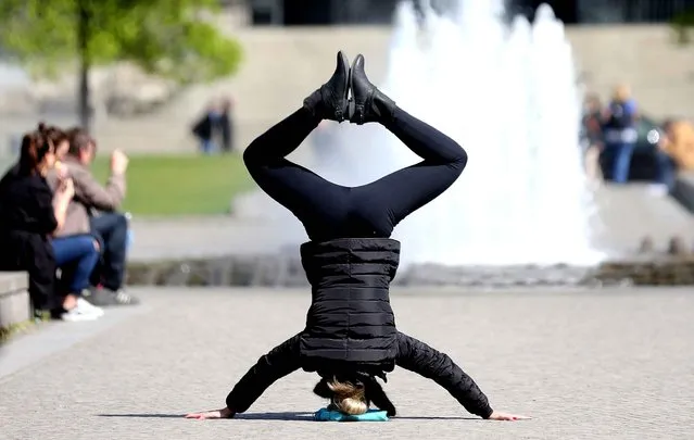 A woman makes a headstand in the Lustgarten park on Museum Island in central Berlin on April 29, 2015. (Photo by Wolfgang Kumm/AFP Photo/DPA)