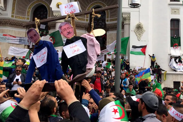 People carry hung effigees with the faces of Algerian businessman Ali Haddad and former prime minister Ahmed Ouyahia, during a protest to push for the removal of the current political structure, in Algiers, Algeria on April 5, 2019. (Photo by Ramzi Boudina/Reuters)
