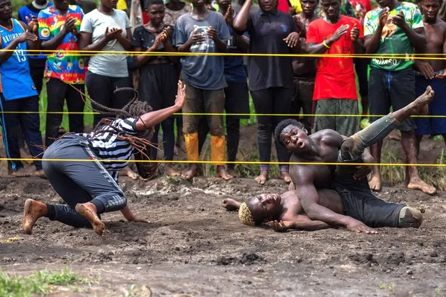 A female referee counts as member of Uganda's Soft Ground Wrestling is pinned to the ground during a training session at their camp in Mukono on February 28, 2024. (Photo by Badru Katumba/AFP Photo)