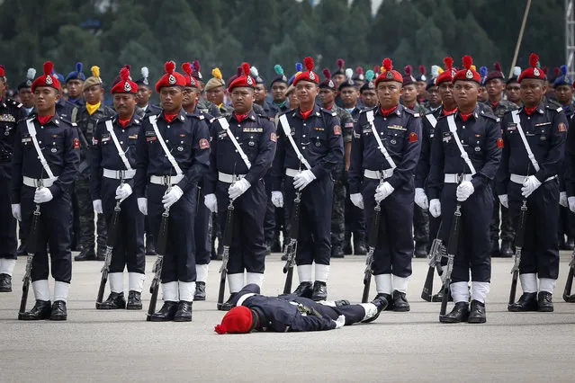 Malaysia's police stand in formation as one of them is fainted due to hot weather on the Police Day in Kuala Lumpur, Malaysia, Friday, March 25, 2016. Malaysian police have detained 15 more suspected Islamic State members, who police say planned to launch attacks and tried to obtain chemicals to make bombs, National police chief said in a statement Thursday. (Photo by Vincent Thian/AP Photo)