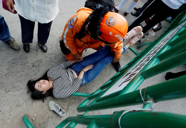 A Colombian civil defense member helps a woman who fainted at the Simon Bolivar international bridge, on the border between Colombia and Venezuela, in Cucuta, Colombia on May 3, 2019. (Photo by Luisa Gonzalez/Reuters)