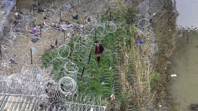 In an aerial view, an immigrant faces coils of razor wire after crossing the Rio Grande from Mexico on March 17, 2024 in Eagle Pass, Texas. Texas National Guard troops have fortified Eagle Pass with vast a amount of razor wire as part of Governor Greg Abbott's “Operation Lone Star” to deter migrants from crossing into Texas. The U.S. southwestern border stretches nearly 2,000 miles, from the Gulf of Mexico to the Pacific Ocean and is marked by fences, deserts, mountains and the Rio Grande, which runs the entire length of Texas. The politics surrounding border and immigration issues have become dominant themes in the U.S. presidential election campaign. (Photo by John Moore/Getty Images)