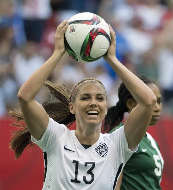 In  this June 16, 2015, file photo,  United States' Alex Morgan celebrates teammate Abby Wambach's goal as Nigeria's Onome Ebi looks on during the first half of a FIFA Women's World Cup soccer match in Vancouver, British Columbia, Canada. Five players from the World Cup-winning U.S. national team have accused the U.S. Soccer Federation of wage discrimination in an action filed with the Equal Employment Opportunity Commission. (Photo by Jonathan Hayward/The Canadian Press via AP Photo)