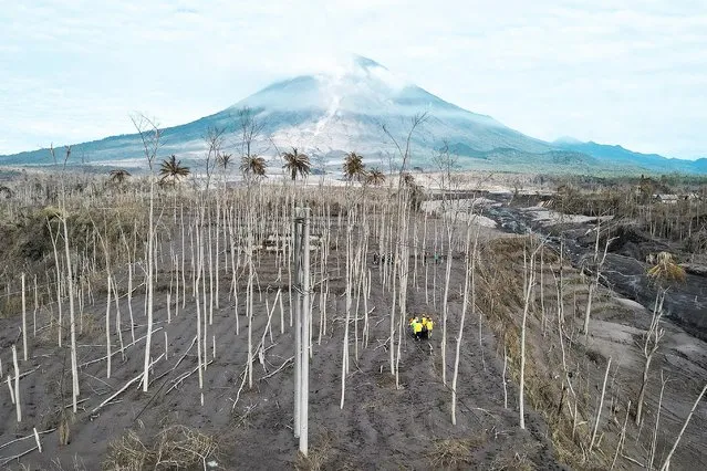 Rescue volunteers carry a body bag at an area affected by the eruption of Mount Semeru volcano in Curah Kobokan, Pronojiwo district, Lumajang, Indonesia, December 7, 2021. Picture taken with a drone. (Photo by Willy Kurniawan/Reuters)