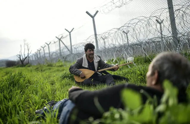 A refugee Refik, from the northern Syrian town of Afrin, plays a string instrument near the border fence at the makeshift camp along the Greek-Macedonian border, near the Greek village of Idomeni on April 1, 2016, where thousands of refugees and migrants are stranded by the Balkan border blockade. (Photo by Bulent Kilic/AFP Photo)