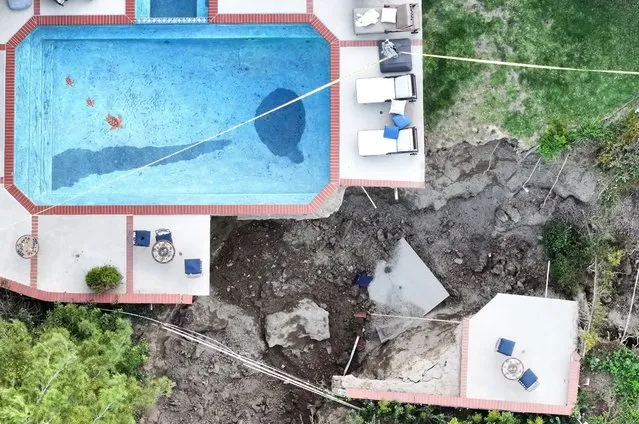 An aerial view shows a pool remaining above a large fissure after a landslide destroyed one home and damaged two others in the Sherman Oaks neighborhood on March 13, 2024 in Los Angeles, California. Recent heavy rains likely played a role in the landslide, prompting several residents to evacuate. Since January 1st, downtown Los Angeles has received nearly twice its average amount of rainfall by this time of year while the city had reported close to 600 mudslides by early February. (Photo by Mario Tama/Getty Images)