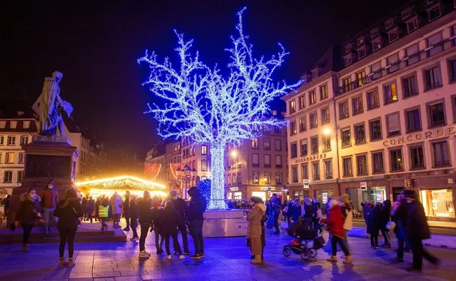 People walk past an illuminated tree at a Christmas market in Strasbourg, France on November 26, 2021. (Photo by Arnd Wiegmann/Reuters)