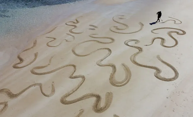 This aerial photo taken on December 3, 2021 shows artist Derek Yung creating a large-scale sand drawing on Sai Wan beach in the Sai Kung area of Hong Kong. (Photo by Peter Parks/AFP Photo)