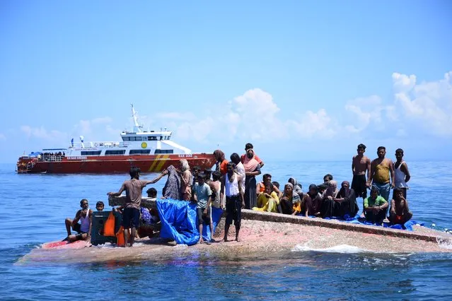  Rohingya refugees wait to be rescued from the hull of their capsized boat as a National Search and Rescue Agency (BASARNAS) vessel approaches in waters some 16 nautical miles (29 kilometers) off west Aceh on March 21, 2024. Indonesian authorities rescued at least 69 Rohingya refugees who had been at sea for weeks and were taking them to shore on March 21 after their boat capsized a day earlier. (Photo by Zahlul Akbar/AFP Photo)