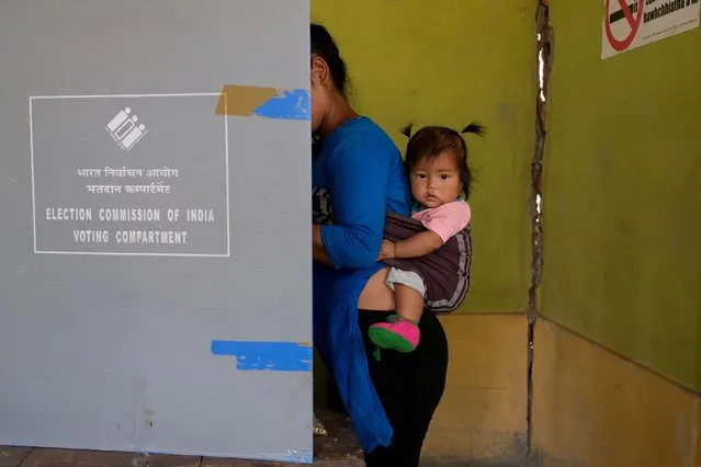 A woman, carrying her daughter, casts her vote at a polling station during the first phase of the general election, in the border village of Zokhawthar, Champhai district, in India's northeastern state of Mizoram, India, on April 19, 2024. (Photo by Chanchinmawia/Reuters)