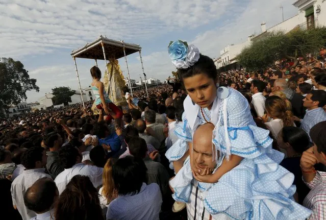 A girl wearing a rociera dress is carried over shoulders of a man during Virgin of El Rocio procession around the shrine of El Rocio in Almonte, southern Spain, May 25, 2015. (Photo by Marcelo del Pozo/Reuters)