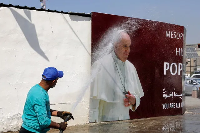 A man sprays water at a poster of Pope Francis ahead of the planned visit of Pope Francis to Iraq, in Baghdad, Iraq on March 3, 2021. (Photo by Khalid al-Mousily/Reuters)