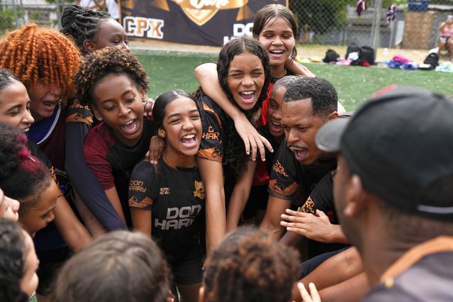 Young women and their coach Dioguinho bring it in for a team huddle at the start of a soccer training session run by the Bola de Ouro social program, at the Complexo da Alemao favela in Rio de Janeiro, Brazil, May 16, 2024. (Photo by Silvia Izquierdo/AP Photo)
