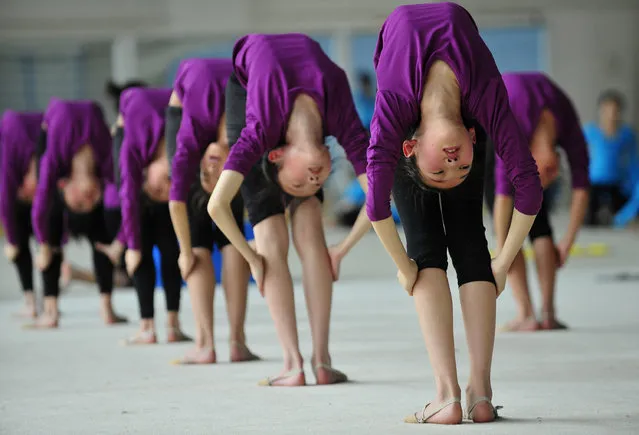 Students stretch during a training session at a gymnastic course at Shenyang Sports School in Shenyang, Liaoning province May 9, 2012. Some 60 students, between the ages of 6 to 15, undergo a nine-year gymnastic programme which includes foundation courses and gymnastic training courses at Shenyang Sports School, and those who are outstanding may be selected to join the national team, according to local media. (Photo by Reuters/Stringer)