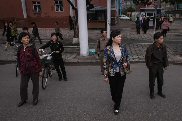 Pedestrians wait to cross a street in Pyongyang on May 6, 2016. When one of the world's most secretive states opens the door to the international media, it keeps a firm grip on the handle. Some 130 journalists flocked to North Korea at the express invitation of the Pyongyang authorities to cover the opening of a rare ruling party congress. They got within 200 meters of the venue, the April 25 Palace, and that was where they were stopped -- on the other side of the road, under a steady drizzle that had been falling on the capital all morning. (Photo by Ed Jones/AFP Photo)