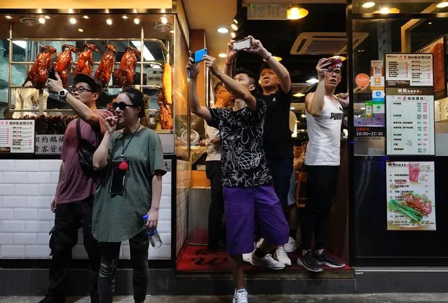 People at a restaurant take pictures of police water cannons in Hong Kong, Sunday, September 29, 2019. Protesters and police clashed in Hong Kong for a second straight day on Sunday, throwing the city's business and shopping belt into chaos and sparking fears of more ugly scenes leading up to China's National Day this week. (Photo by Vincent Yu/AP Photo)