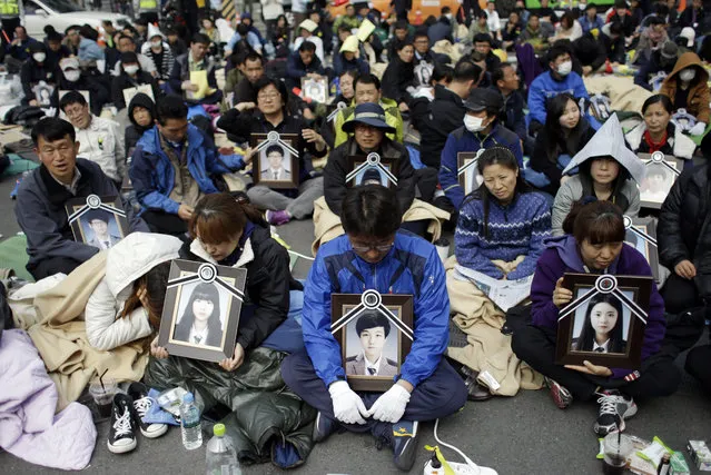 Family members holding the portraits of the victims of the sunken ferry Sewol, sit on a street near the presidential Blue House in Seoul, South Korea, Friday, May 9, 2014. (Photo by Lee Jin-man/AP Photo)