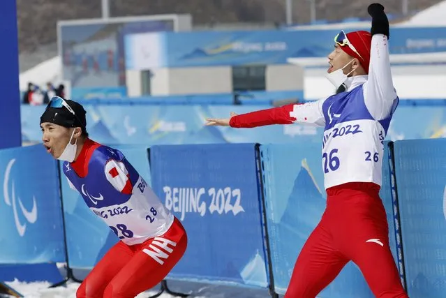 Chenyang Wang #28 of Team China reacts after winning the gold medal as Jiayun Cai #26 of Team China looks on following the Men's Middle Distance Free Technique Standing on day eight of the Beijing 2022 Winter Paralympics at Zhangjiakou National Biathlon Centre on March 12, 2022 in Zhangjiakou, China. (Photo by Issei Kato/Reuters)