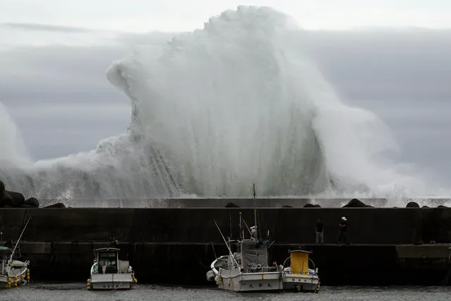 Men look at fishing boats as surging waves hit against the breakwater while Typhoon Hagibis approaches at a port in town of Kiho, Mie Prefecture, Japan Friday, October 11, 2019. A powerful typhoon is advancing toward the Tokyo area, where torrential rains are expected this weekend. (Photo by Toru Hanai/AP Photo)