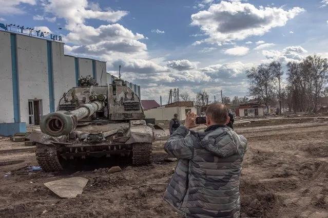 A resident takes photos of a destroyed Russian tank next to the railway station where the Russian forces were stationed, in the recaptured by the Ukrainian army Trostyanets town, in Sumy region, Ukraine, 29 March 2022 (issued 30 March 2022). Trostyanets was recaptured by the Ukrainian army after the town was under Russian forces from the first days of the war for over a month. Russian troops entered Ukraine on 24 February prompting the country's president to declare martial law and triggering a series of announcements by Western countries to impose severe economic sanctions on Russia. (Photo by Roman Pilipey/EPA/EFE)
