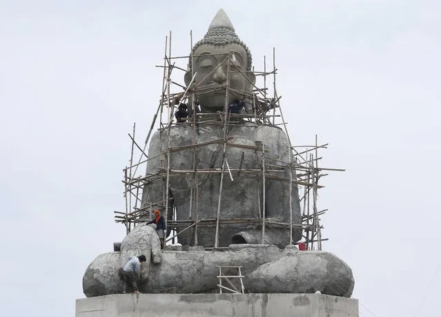 In this Monday, April 17, 2017 photo, workers stand on scaffolding around a giant Buddha statue at Tapong Nok temple in Rayong province, eastern Thailand. Thailand is a predominately Buddhist nation. (Photo by Sakchai Lalit/AP Photo)