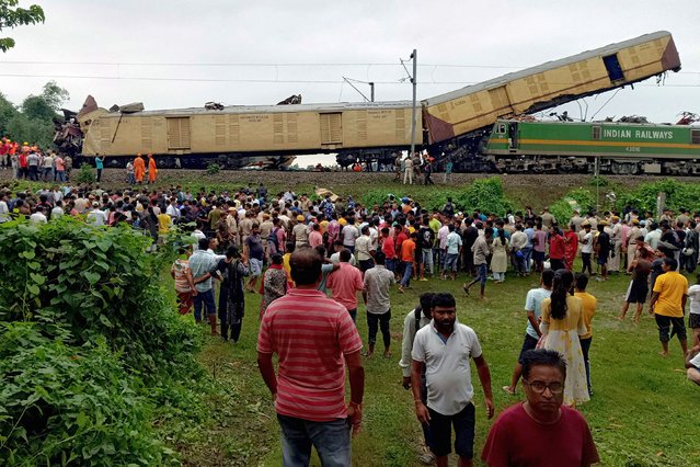 People look on at the site of a collision between an express passenger train and a goods train in Nirmaljote, near Rangapani station in India's West Bangal state on June 17, 2024. At least seven people were killed when the trains collided on June 17 in India's West Bengal state, derailing three passenger carriages, police said. (Photo by Diptendu Dutta/AFP Photo)