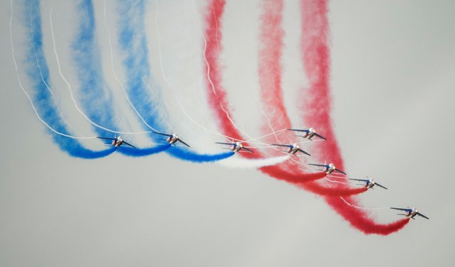 Alphajet aircrafts from the French elite acrobatic flying team “Patrouille de France” (PAF) perform aerobatics and release trails of blue, white and red smokes, representing the French national flag's colours, as they fly over the 701 Air Base in Salon-de-Provence, southern France, on May 18, 2023. The PAF organizes its 70th anniversary celebration during an aerial meeting occurring on May 20 and 21, 2023. (Photo by Clement Mahoudeau/AFP Photo)