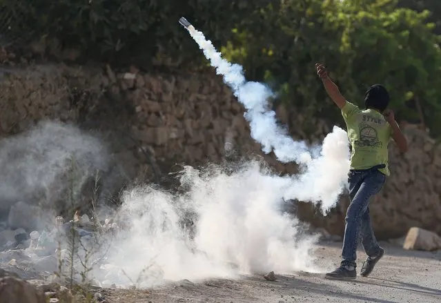 A Palestinian protester returns a tear gas canister fired by Israeli troops during clashes following the funeral of Palestinian youth Laith al-Khaldi, in Jalazoun refugee camp near the West Bank city of Ramallah August 1, 2015. Al-Khaldi died on Saturday at a West Bank hospital following a clash with Israeli troops near Ramallah, Palestinian hospital officials said. (Photo by Mohamad Torokman/Reuters)