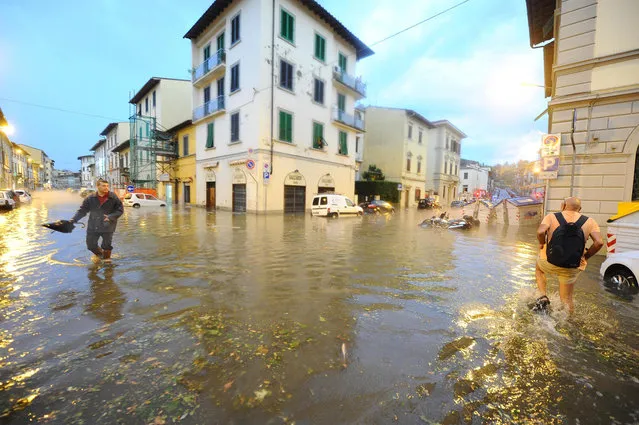 In this picture taken Saturday, August 1, 2015, people make their way on a flooded street in Florence, Italy. (Photo by Maurizio Degl'Innocenti/ANSA Via AP Photo)