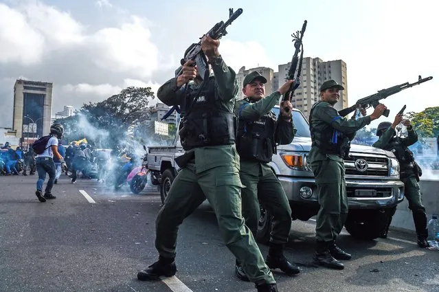 Members of the Bolivarian National Guard who joined Venezuelan opposition leader and self-proclaimed acting president Juan Guaido fire into the air to repel forces loyal to President Nicolas Maduro who arrived to disperse a demonstration near La Carlota military base in Caracas on April 30, 2019. Guaido – accused by the government of attempting a coup Tuesday – said there was “no turning back” in his attempt to oust President Nicolas Maduro from power. (Photo by Federico Parra/AFP Photo)