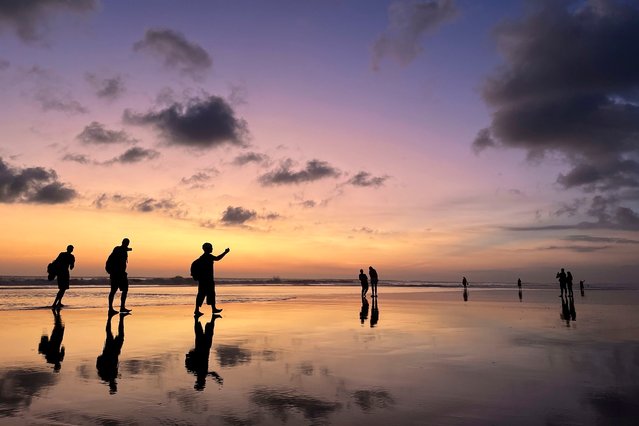 Tourists laugh and take selfies at sunset on Seminyak Beach in Bali on Thursday, September 5, 2024. (Photo by Adam Schreck/AP Photo)