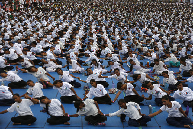 Indians holds hands as they attempt to create a record for the longest human yoga chain with more than 8000 participants at an event to celebrate International Yoga Day in Ahmadabad, India, Tuesday, June 21, 2016. Millions of yoga enthusiasts are bending their bodies in complex postures across India as they take part in a mass yoga program to mark the second International Yoga Day. (Photo by Ajit Solanki/AP Photo)