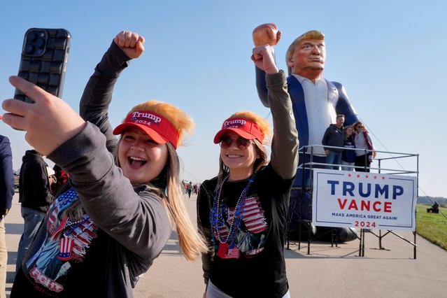 Faith Rail, right, and Kellie Kamphuis take a selfie in front of an inflatable of Republican presidential nominee former President Donald Trump before he speaks at a campaign stop at the Dodge County Airport Sunday, October 6, 2024, in Juneau, Wis. (Photo by Morry Gash/AP Photo)