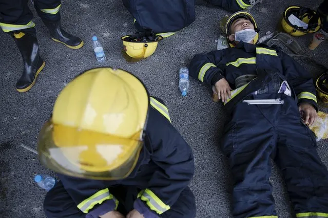 Firefighters take a break after trying to put fire down at the explosion site in Binhai new district in Tianjin, China August 13, 2015. (Photo by Damir Sagolj/Reuters)