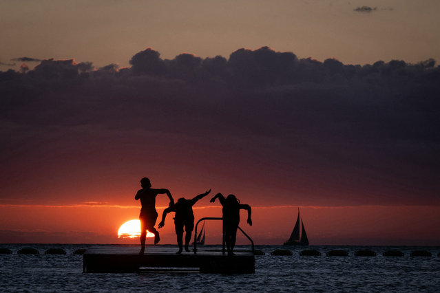 People dive from a platform in the sea at sunset in Noumea on the French overseas collectivity of New-Caledonia on September 25, 2024. (Photo by Sébastien Bozon/AFP Photo)