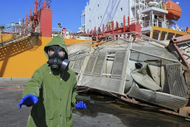 Experts investigate at the site of a toxic gas explosion in Jordan's Red Sea port of Aqaba, Tuesday, June 28, 2022. A crane loading chlorine tanks onto a ship on Monday dropped one of them, causing an explosion of toxic yellow smoke that killed over a dozen people and sickened some 250, authorities said. (Photo by Raad Adayleh/AP Photo)