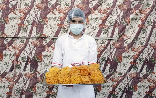 An Iranian worker holds a tray of “Zoolbia” which is a special sweet traditionally served for Ramdan, in a kitchen of a sweets shop in Tehran, Iran, 04 April 2022. “Zoolbia and Bamieh” is the main sweets for the Iftar time for the Iranians. Muslims around the world celebrate the holy month of Ramadan by praying during the night time and abstaining from eating, drinking, and sexual acts during the period between sunrise and sunset. Ramadan is the ninth month in the Islamic calendar and it is believed that the revelation of the first verse in the Koran was during its last 10 nights. (Photo by Abedin Taherkenareh/EPA/EFE)